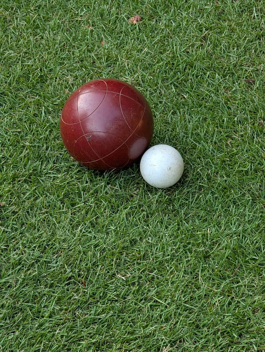 Bocce ball and golf ball sitting on dense low-cut zoysia turf